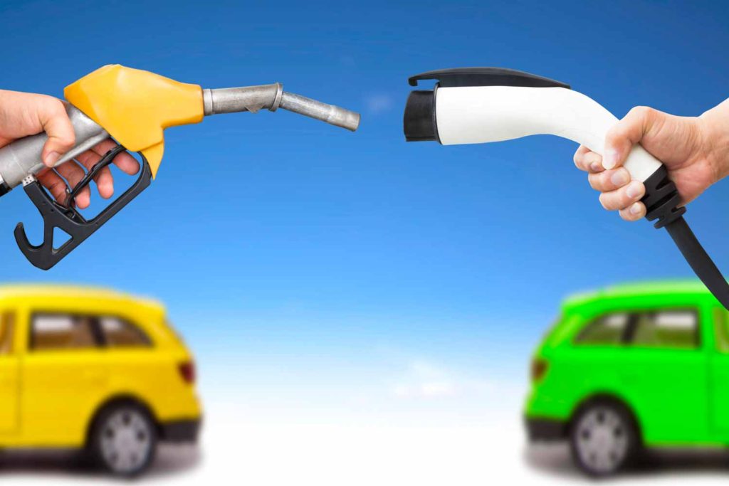 Hands holding fuel pump and EV charger with yellow and green car just seen in background - choosing the best fuel type for cars with our guide