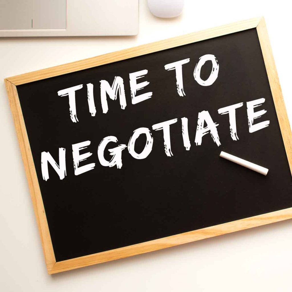 Text TIME TO NEGOTIATE written in chalk on a chalkboard - our essential negotiating tips for buying a used car