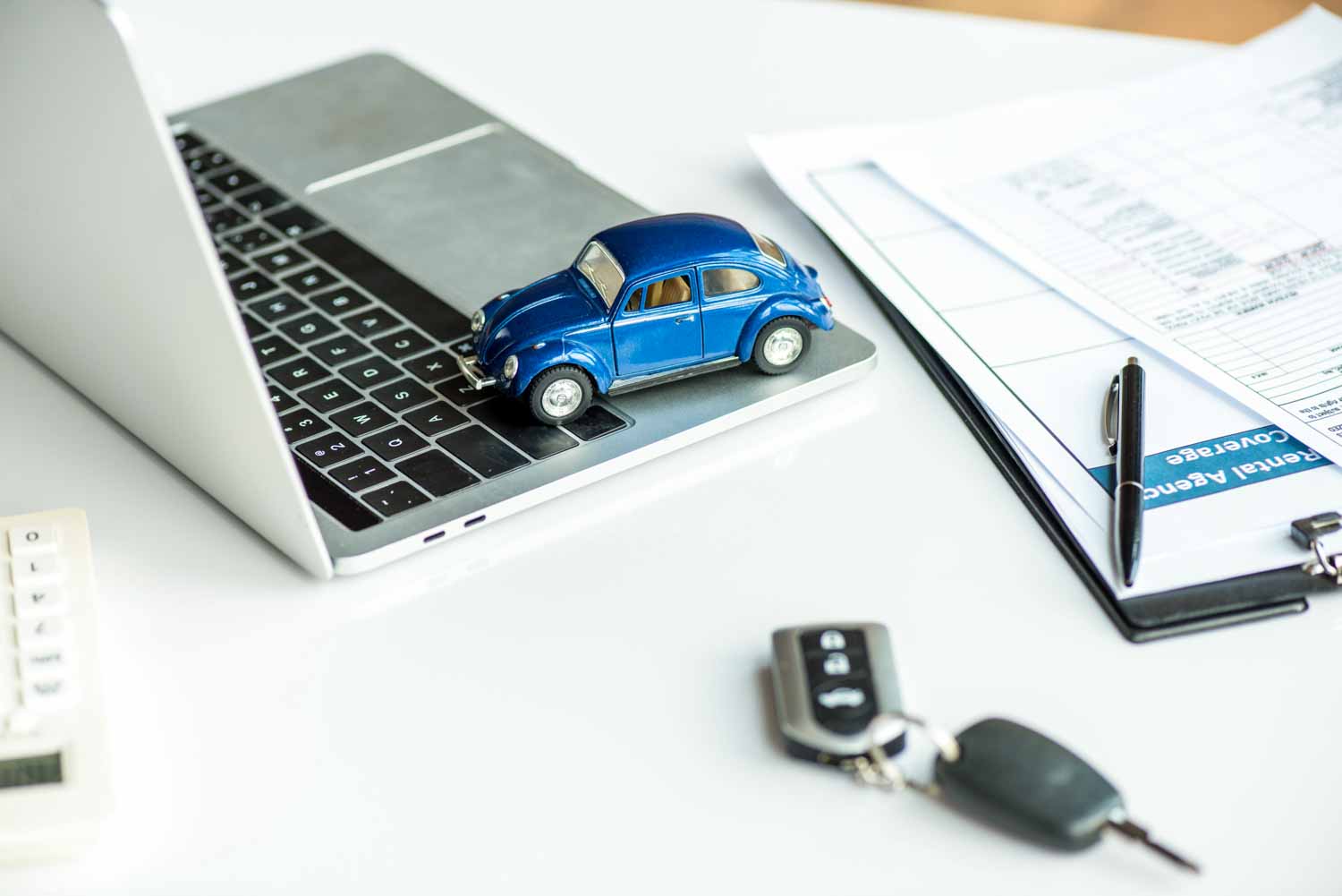 Blue toy car on a laptop keyboard with car keys and paperwork nearby - why you need a car data check before buying